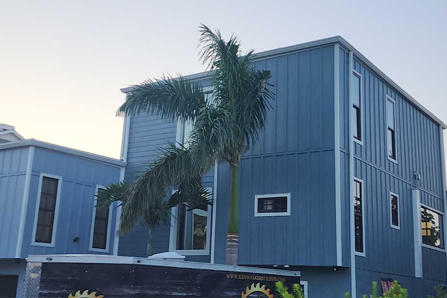 Blue ADU exterior with palm tree and builder sign