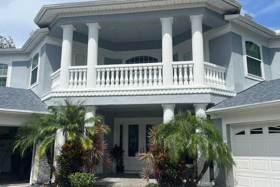 Blue columned home addition with balcony and palms