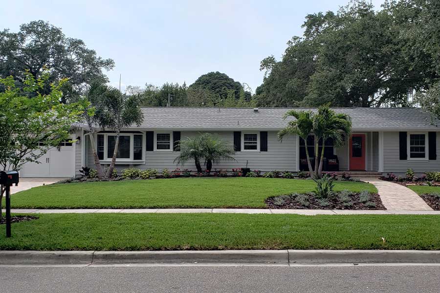 Completed gray home with red door and landscaping
